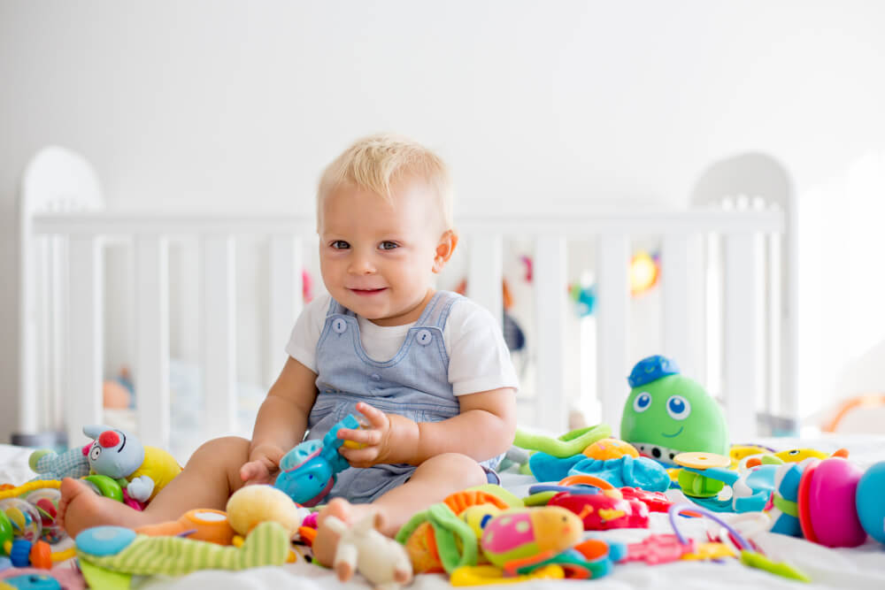 baby toddler boy playing many colorful toys